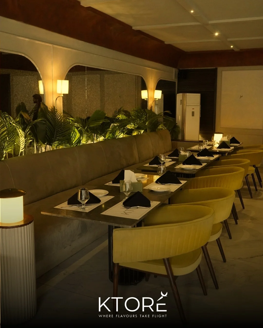 A long velvet banquette with chartreuse chairs, arched mirrors and warm sconces