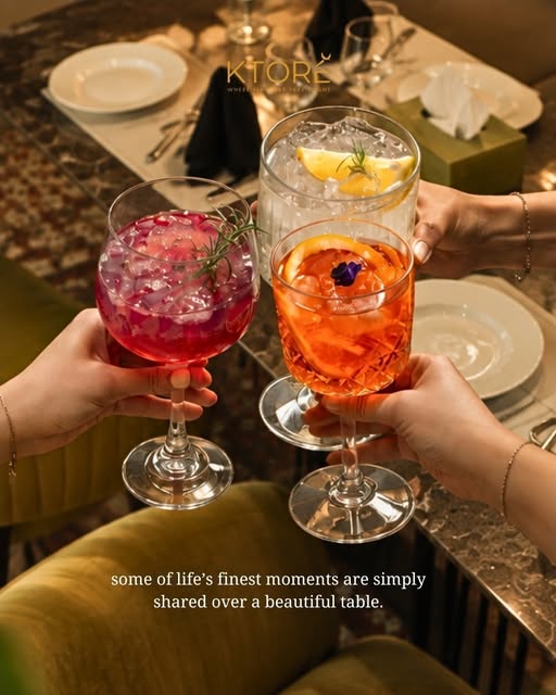 Three glasses raised over a set table — berry, citrus and orange mocktails